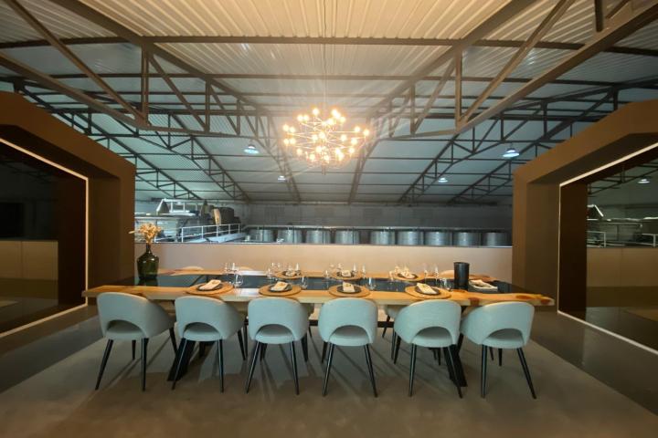 Elegant dining table setup with eight chairs under a chandelier in a modern industrial setting.