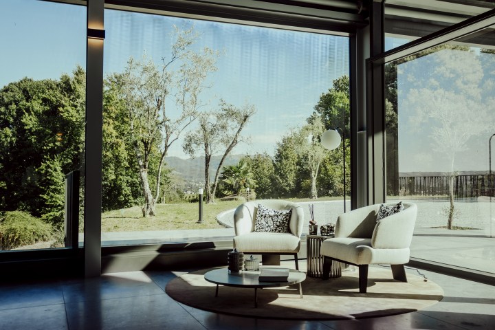 Modern living room with large window overlooking trees and a garden.