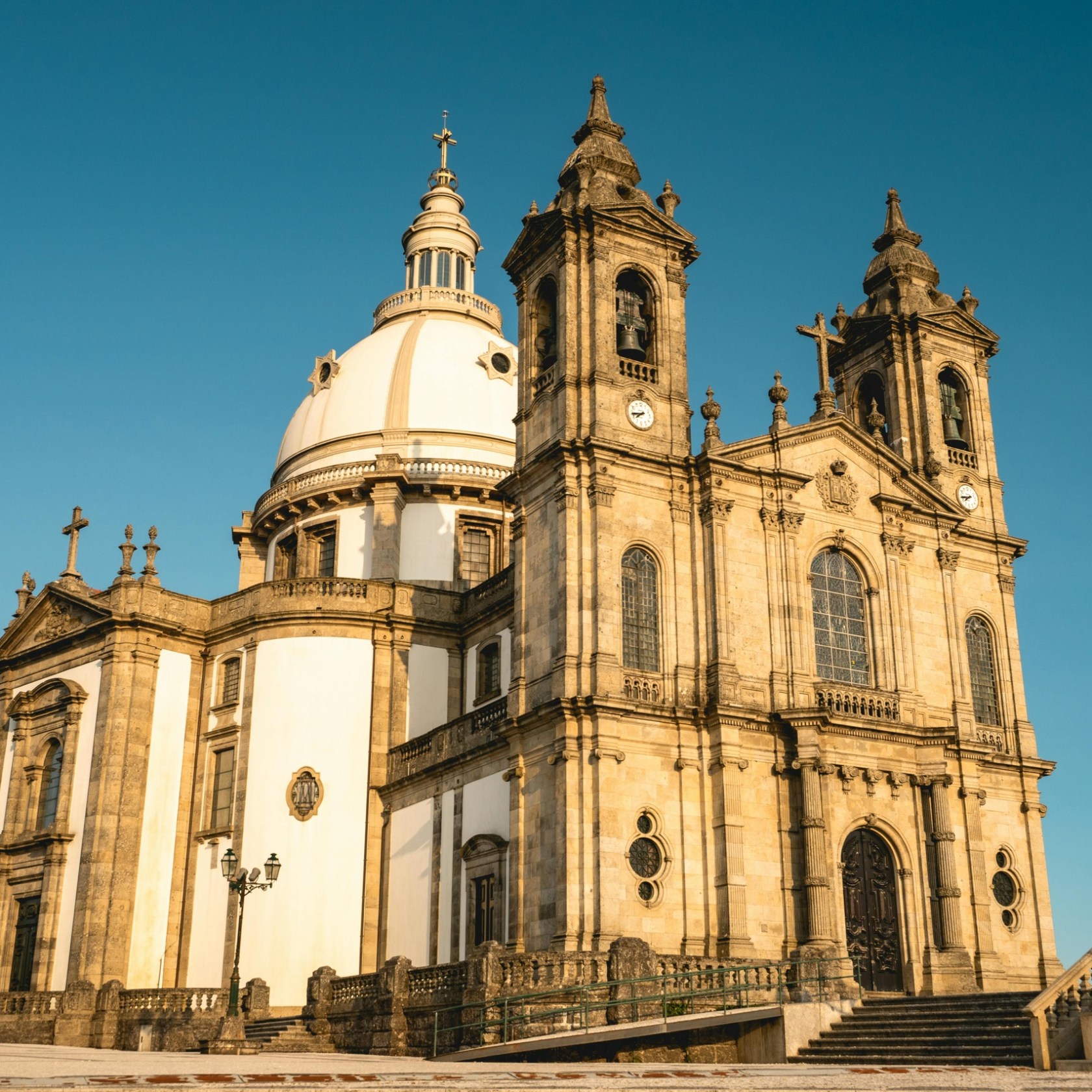 A large historical cathedral with a dome and twin towers under a clear blue sky.