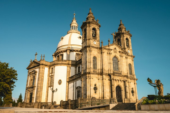 A large historical cathedral with a dome and twin towers under a clear blue sky.