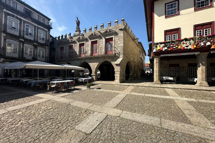 Sunlit stone plaza with historical buildings and outdoor seating.