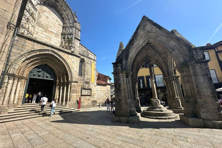 Historic stone church and arched monument under a clear blue sky.