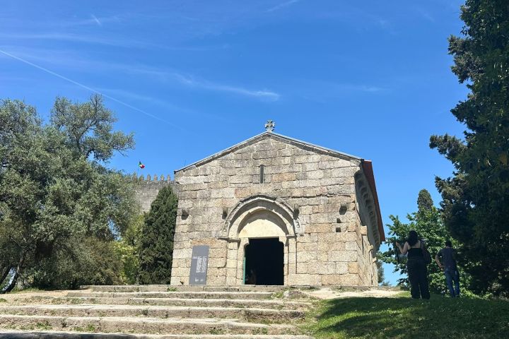 Stone chapel with archway, stairs, and clear blue sky.