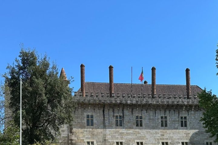 Historic stone building and statue with steps on a sunny day.
