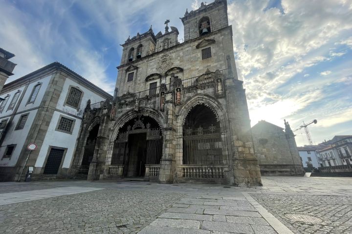 Historic stone cathedral with arched entrances and cloudy sky.