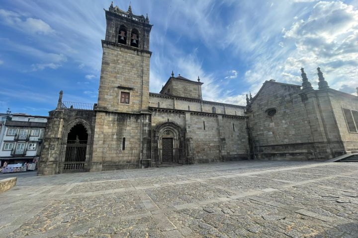 Historic stone church with tall tower under a partly cloudy sky.