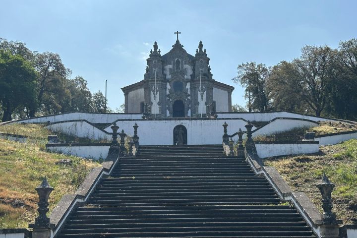 Stone staircase leading to a historic church with trees in the background.