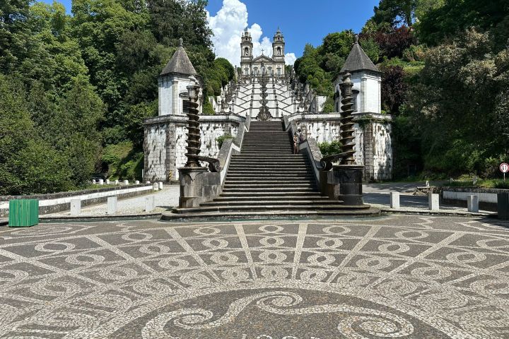 Stone staircase with ornate pillars and trees under a clear blue sky.