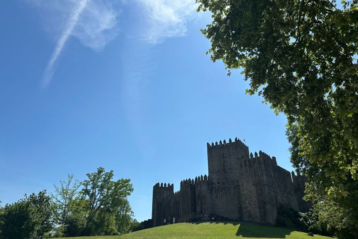 Medieval castle with blue sky and trees in the foreground.