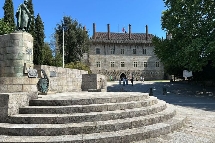 Stone monument and historic building with visitors on a sunny day.