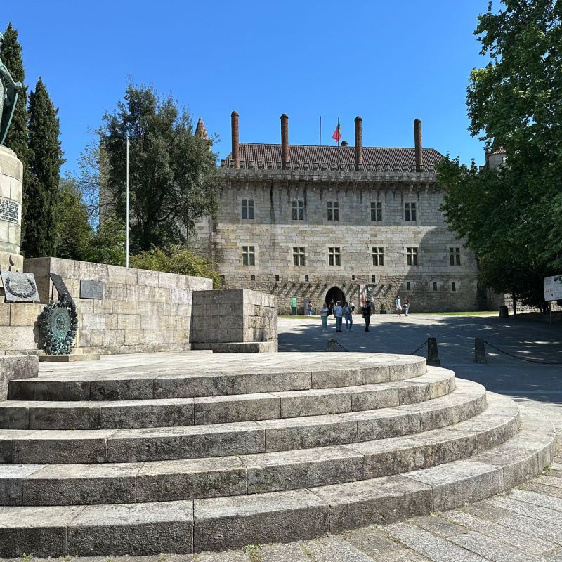 Stone monument and historic building with visitors on a sunny day.
