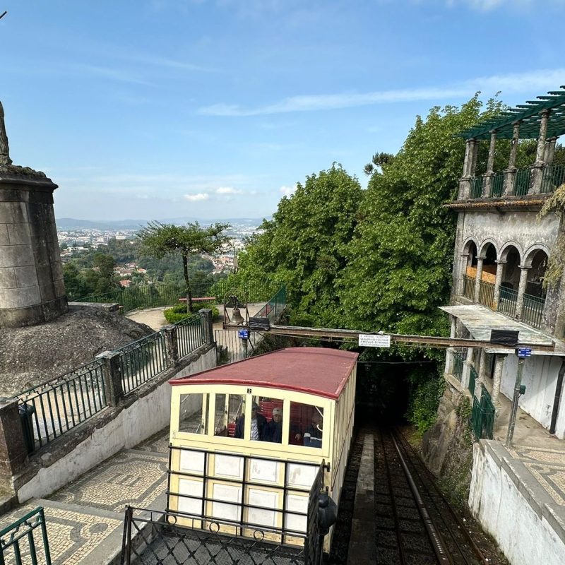 Funicular near a statue of a rider on horseback and trees on a clear day.